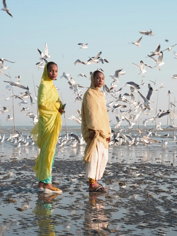 Twee meisjes uit Bandar Abbas staan ​​tussen trekvogels aan de kust van een van de wijken van de stad