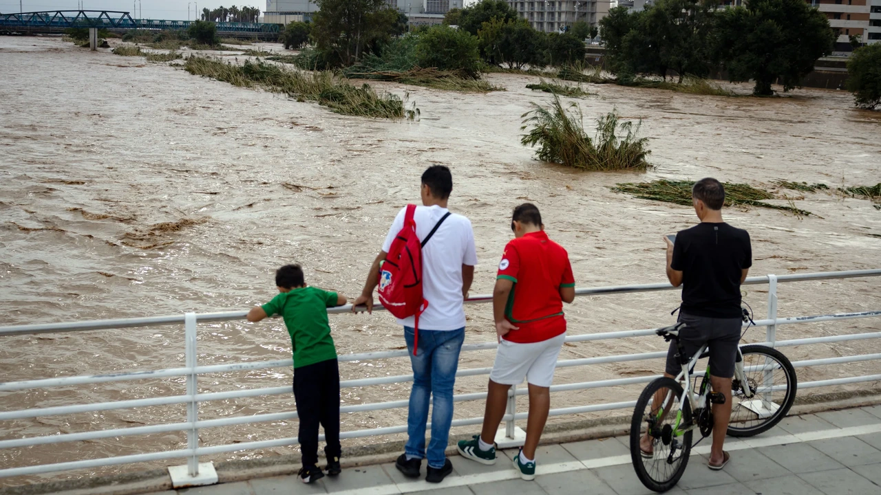 Mensen kijken naar de rivier de Besos die buiten de oevers is getreden