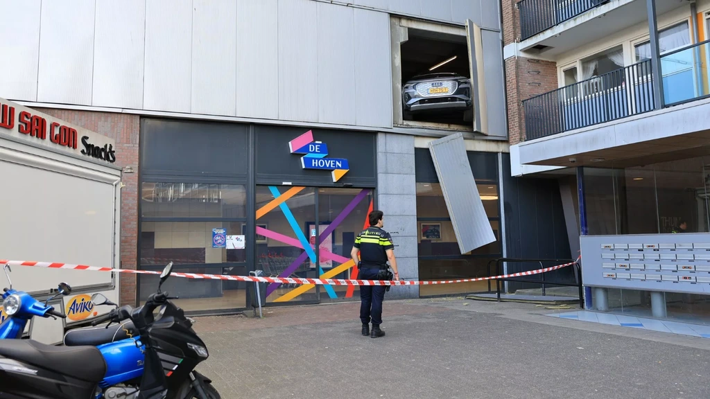 Auto rijdt door muur en hangt uit parkeergarage Delft na onwelwording bestuurder